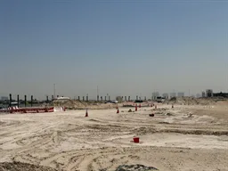 Cleared sand with piling rigs in the distance at Palmiera Collective, The Oasis